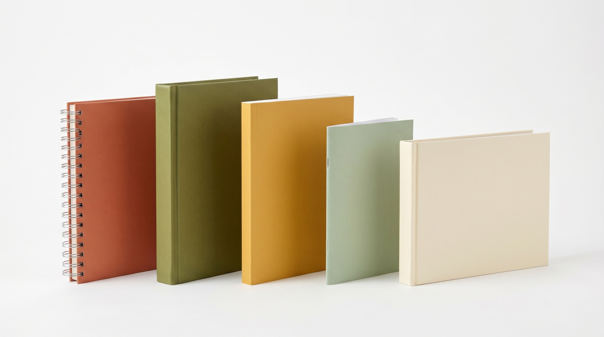 Five custom cookbooks in different binding types - spiral, hardcover, perfect bound, saddle stitch, and landscape - in warm kitchen color tones