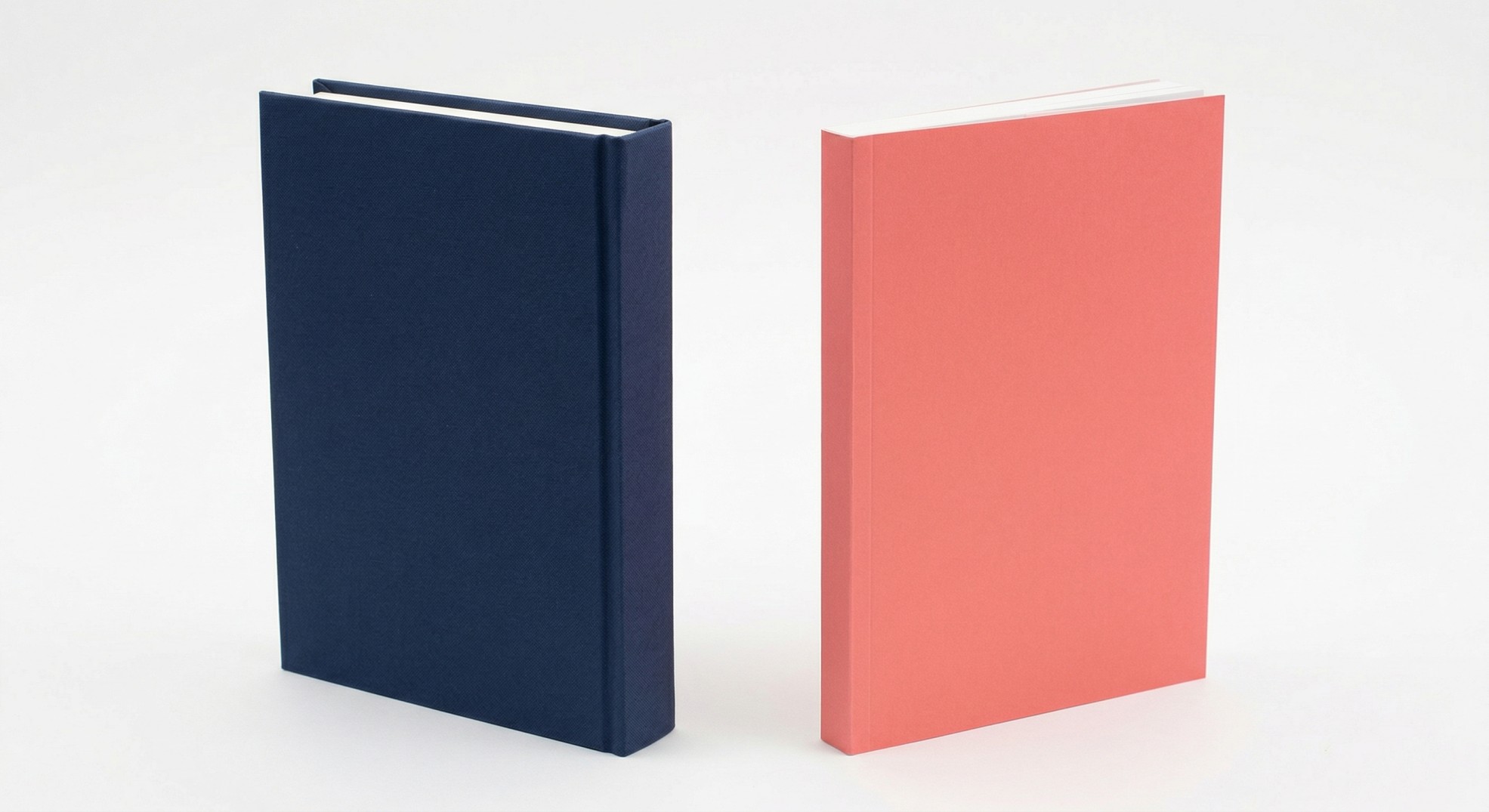 Side by side comparison of a navy hardcover book with rigid squared spine and a coral perfect bound paperback with flat spine, both 6x9 trim